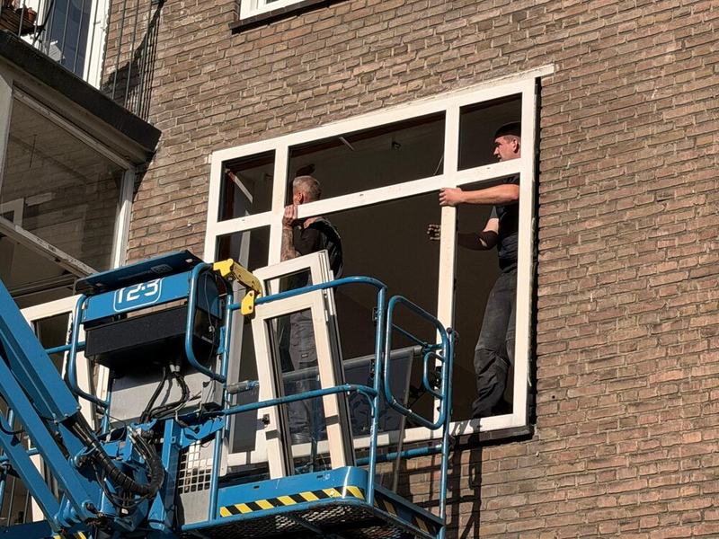 Monteurs plaatsen een nieuw kozijn vanuit de hoogwerker